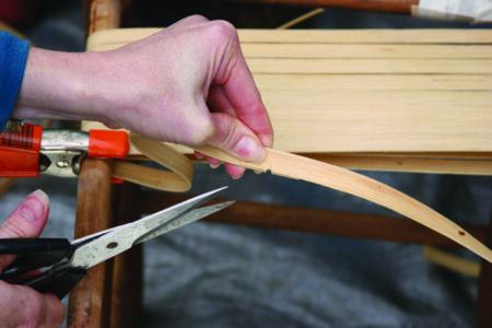 closeup of a hand holding a pair of utility scissors for cutting a reed.